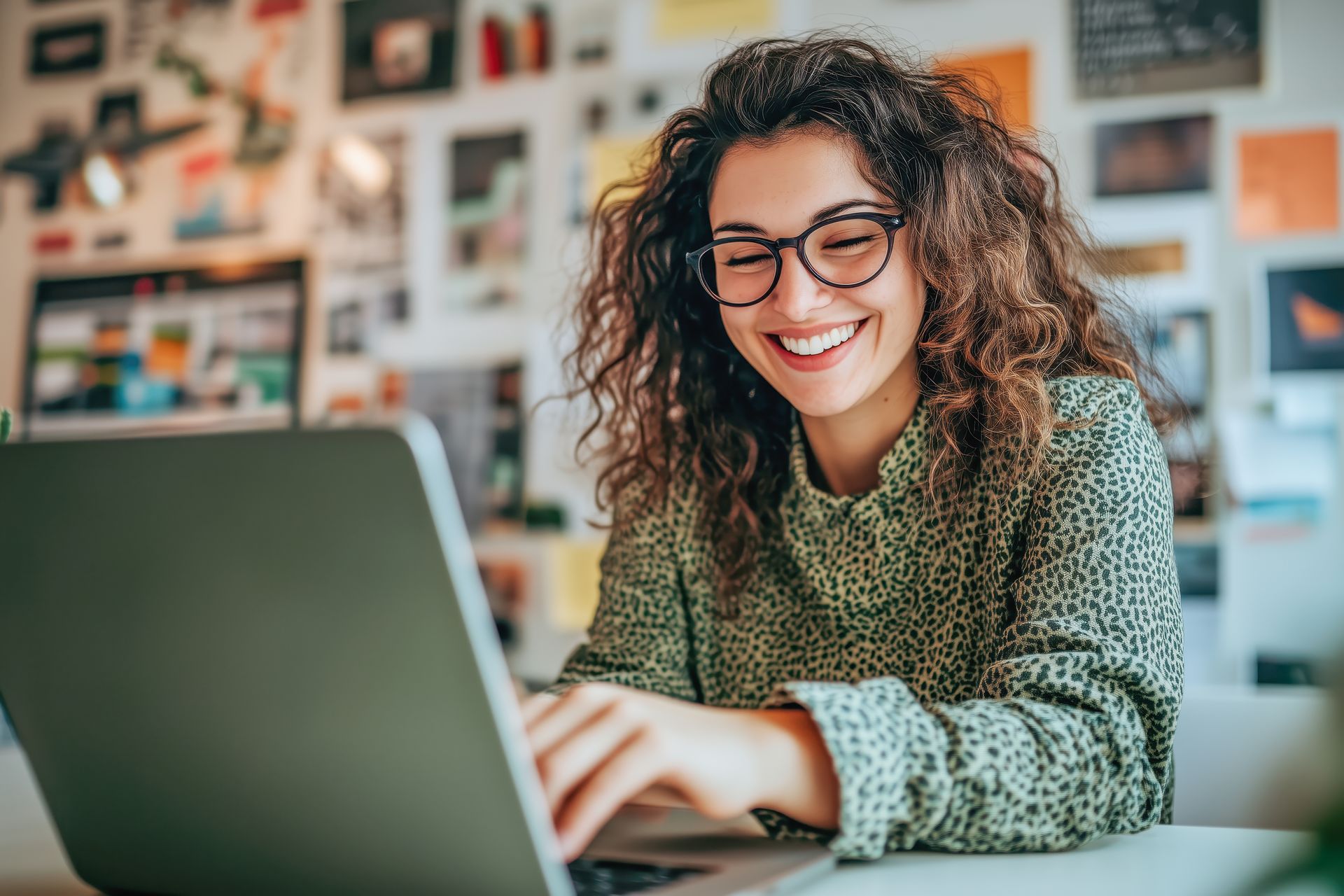 A woman is smiling while using a laptop computer.