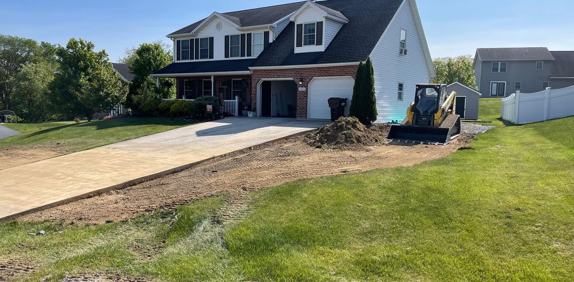 A bulldozer is moving dirt in front of a house.