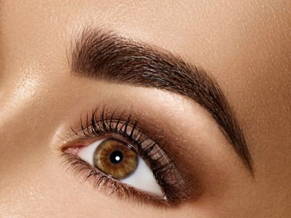 Close-up of a brown eye with dark brown, filled-in eyebrow and smoky eyeshadow.