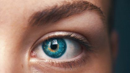 Close-up of a blue eye with a dark pupil, light brown eyebrow, and fair skin.
