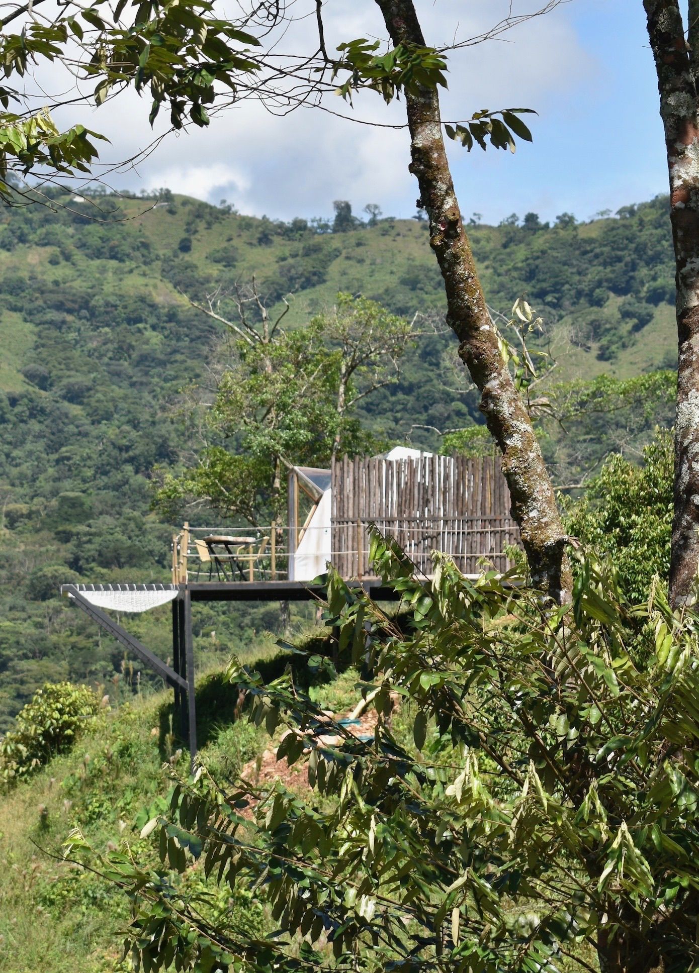 Estructura de plataforma de madera con bañera con vistas a una exuberante ladera verde.