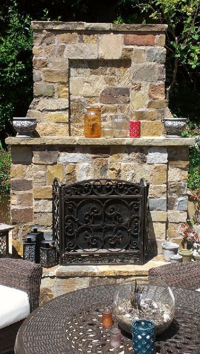 There is a stone fireplace in the backyard with candles on it.