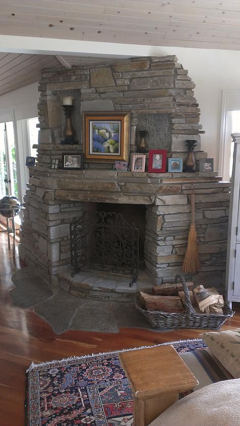 A living room with a stone fireplace and a painting on the mantle.