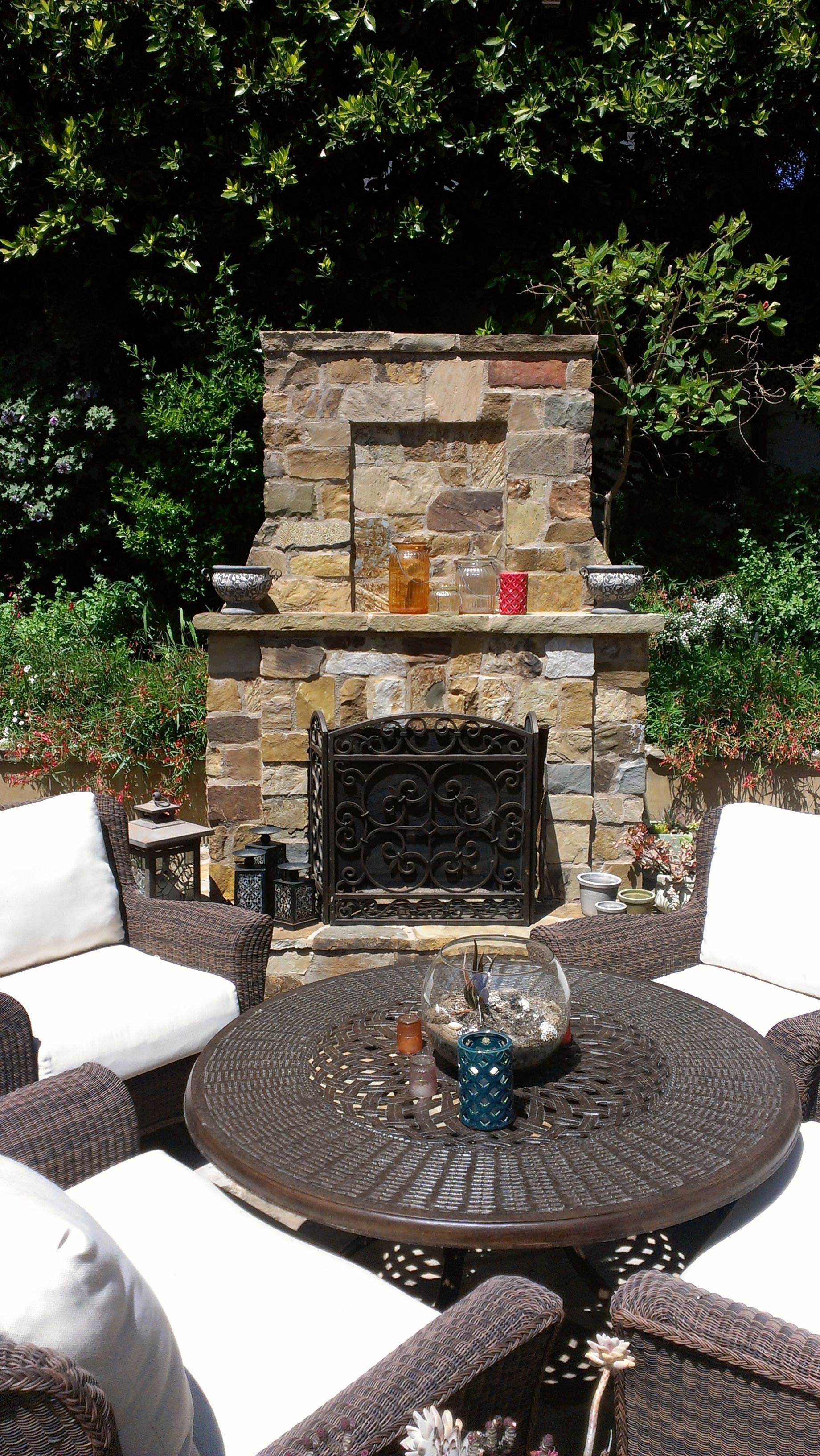 There is a fireplace in the backyard with a table and chairs in front of it.