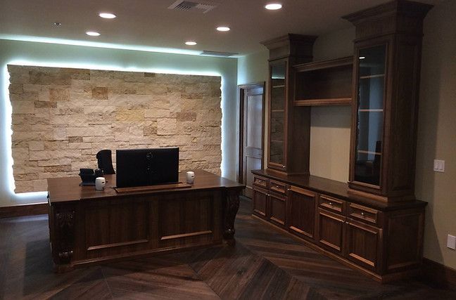 A room with a desk and a tv on it displaying interior stonework on the wall.