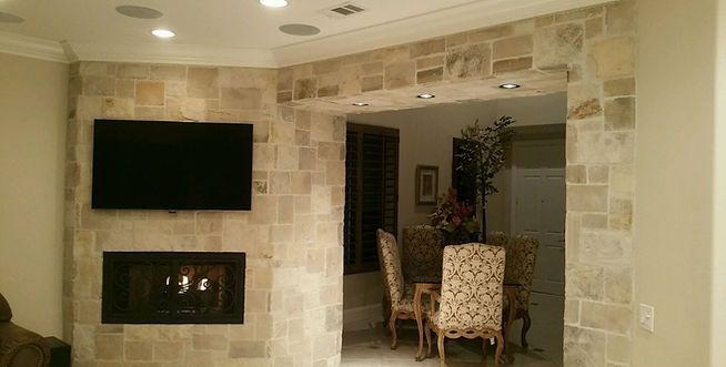 A living room with a fireplace and a flat screen tv built into a stone wall.