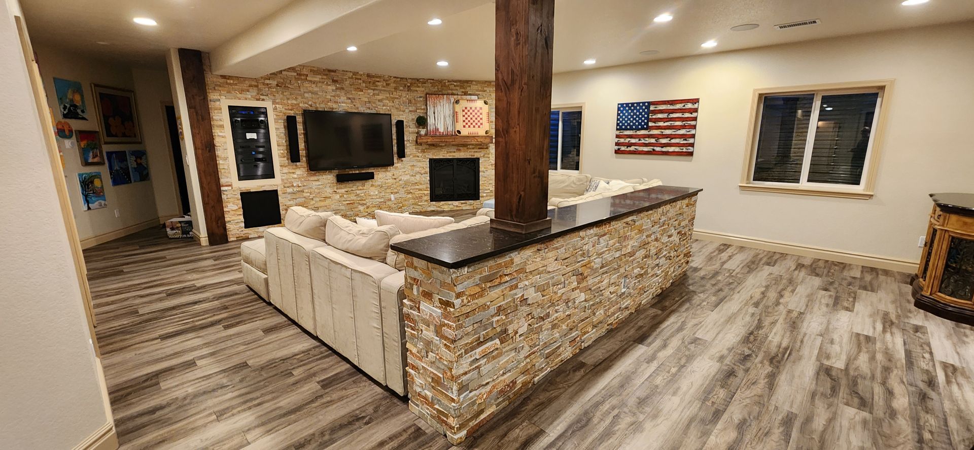 Living room with stone accent walls, fireplace, TV, and American flag art.