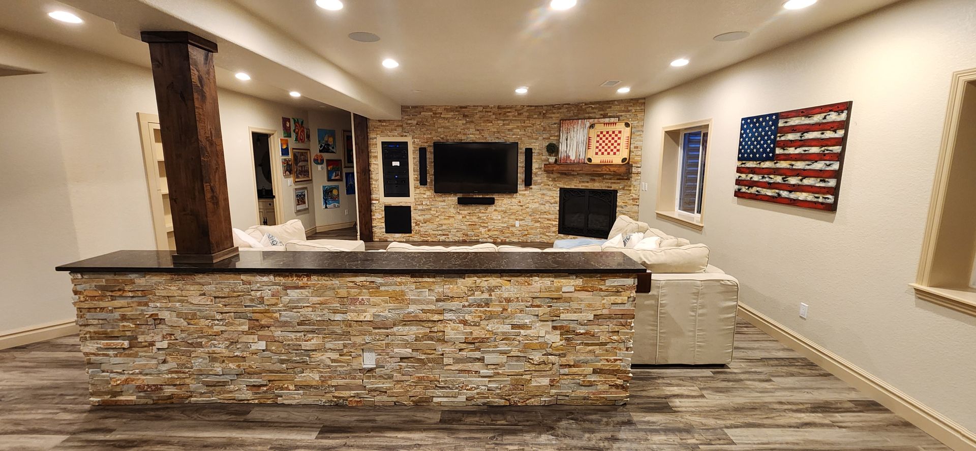 A finished basement with a stone wall, bar, and American flag art.