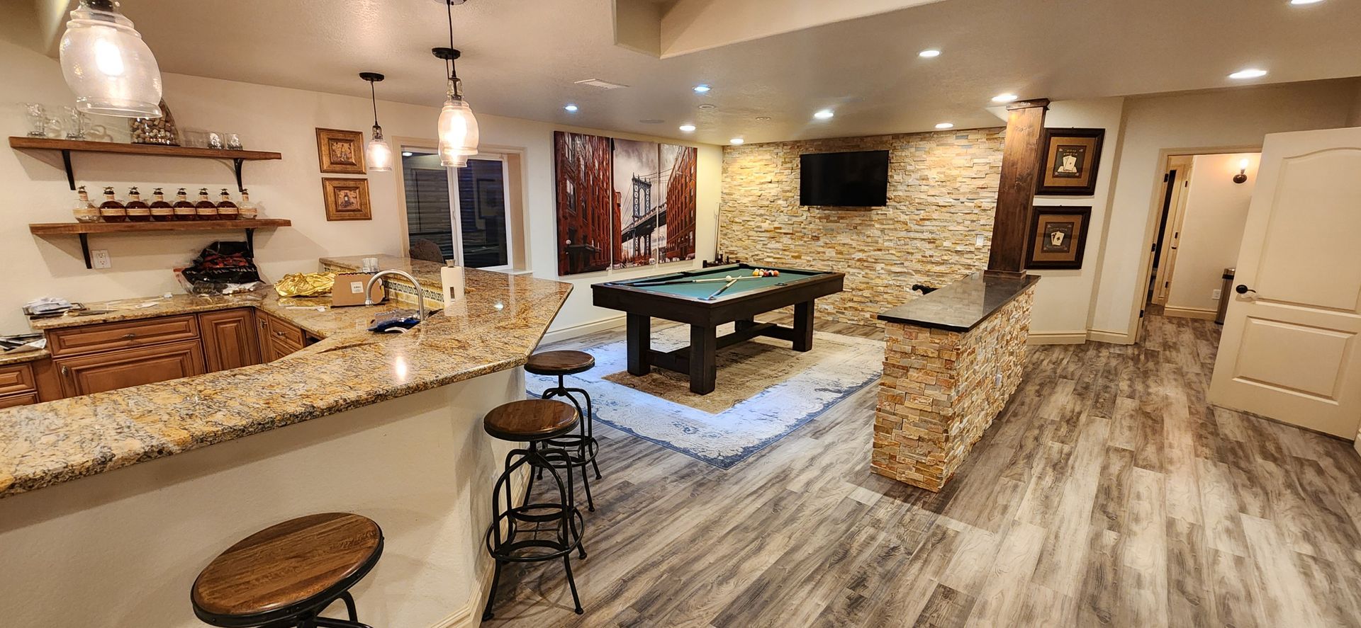 A finished basement with a bar, pool table, and stone accent walls.