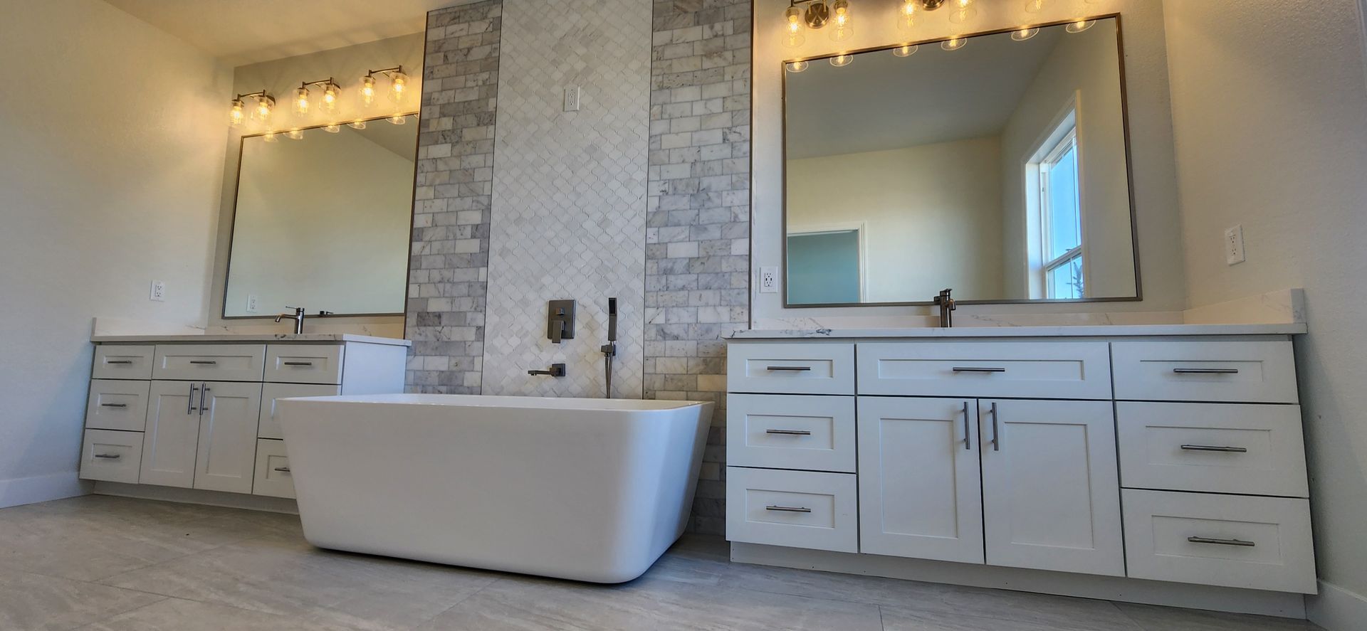 Modern bathroom with white vanity, bathtub, and large mirrors.