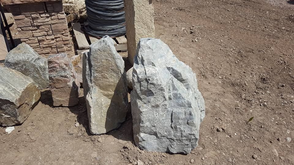 Large gray and tan rocks on brown dirt, likely for landscaping.