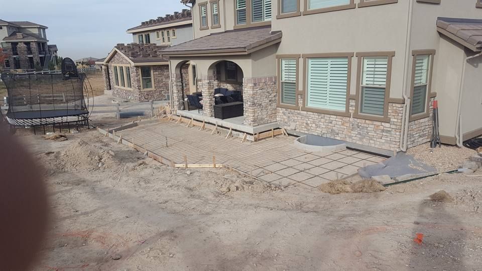 Construction site: house with a patio area under construction, rebar, dirt, and concrete forms.