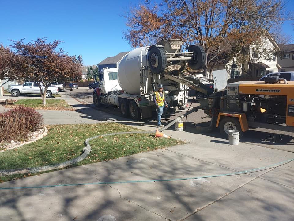 Concrete truck pouring concrete into a pump on a residential driveway on a sunny day.