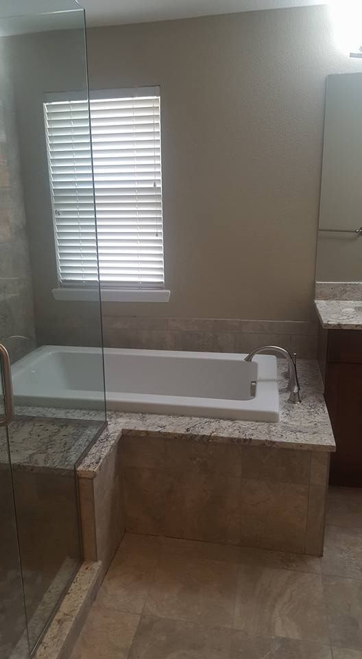 Bathroom with bathtub, tiled walls, and a window with closed blinds.