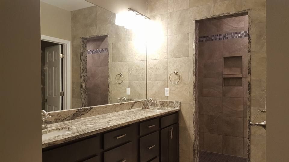 Bathroom with dark cabinets, granite countertop, tiled walls, and a large mirror.