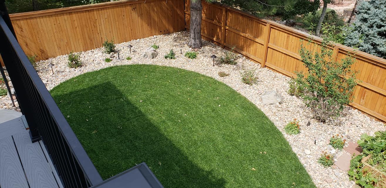 Overhead view of a backyard with a grass area surrounded by a gravel path and wooden fence.