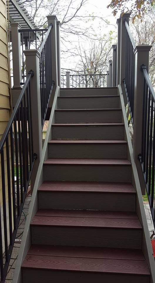Wooden outdoor stairs leading upwards with gray and black railings.