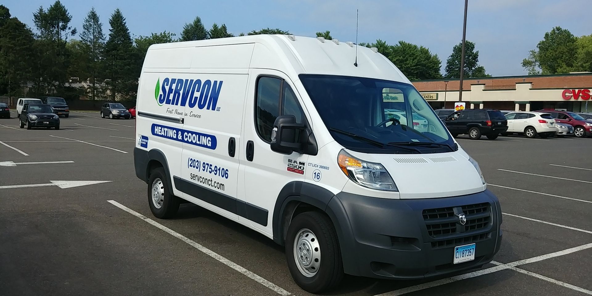A white van is parked in a parking lot in front of a store.