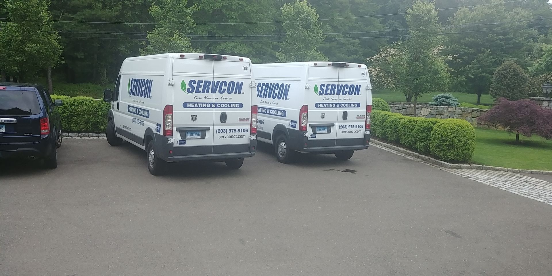 Three white vans are parked in a driveway.