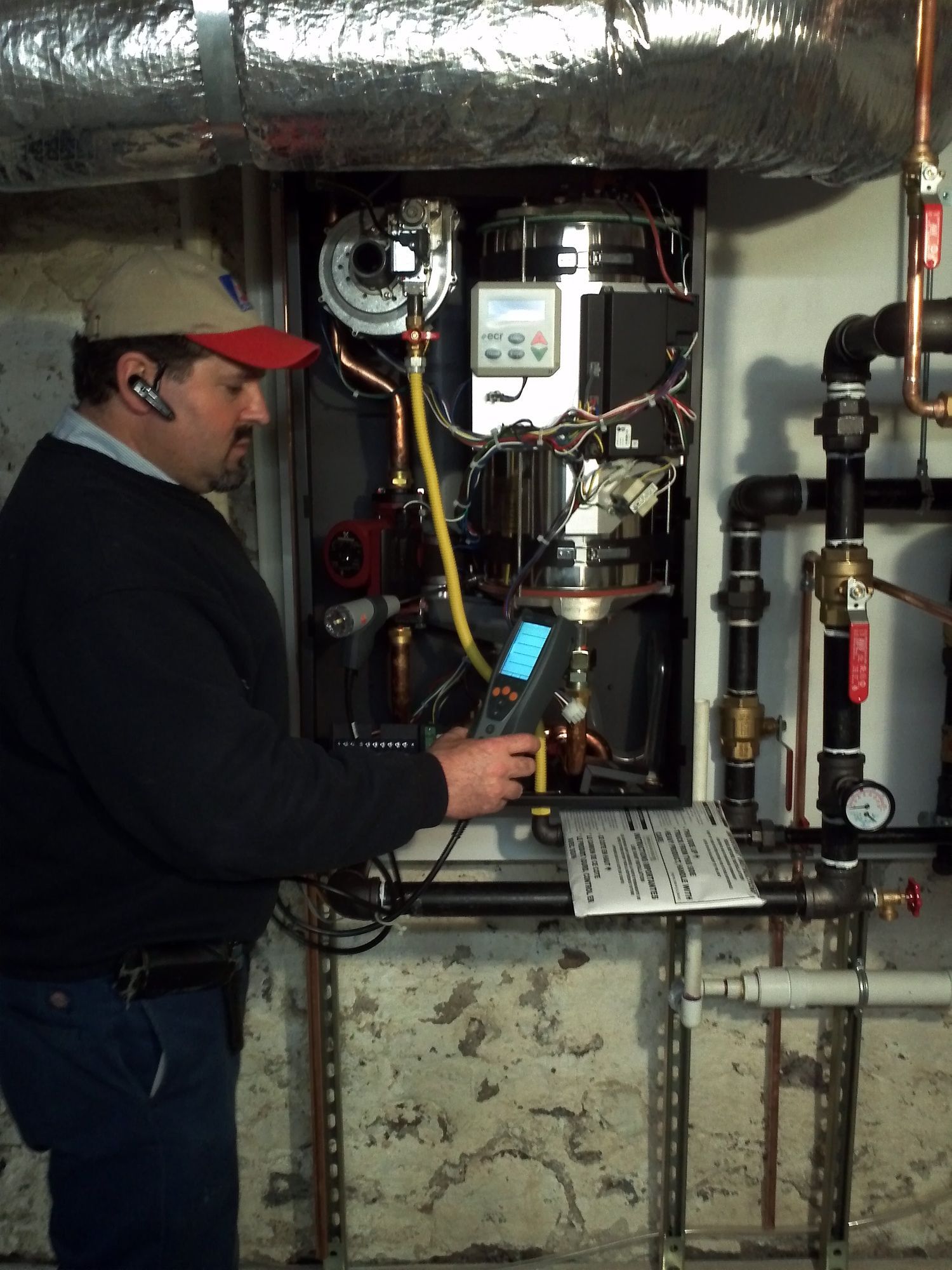 A man in a red hat is working on a boiler