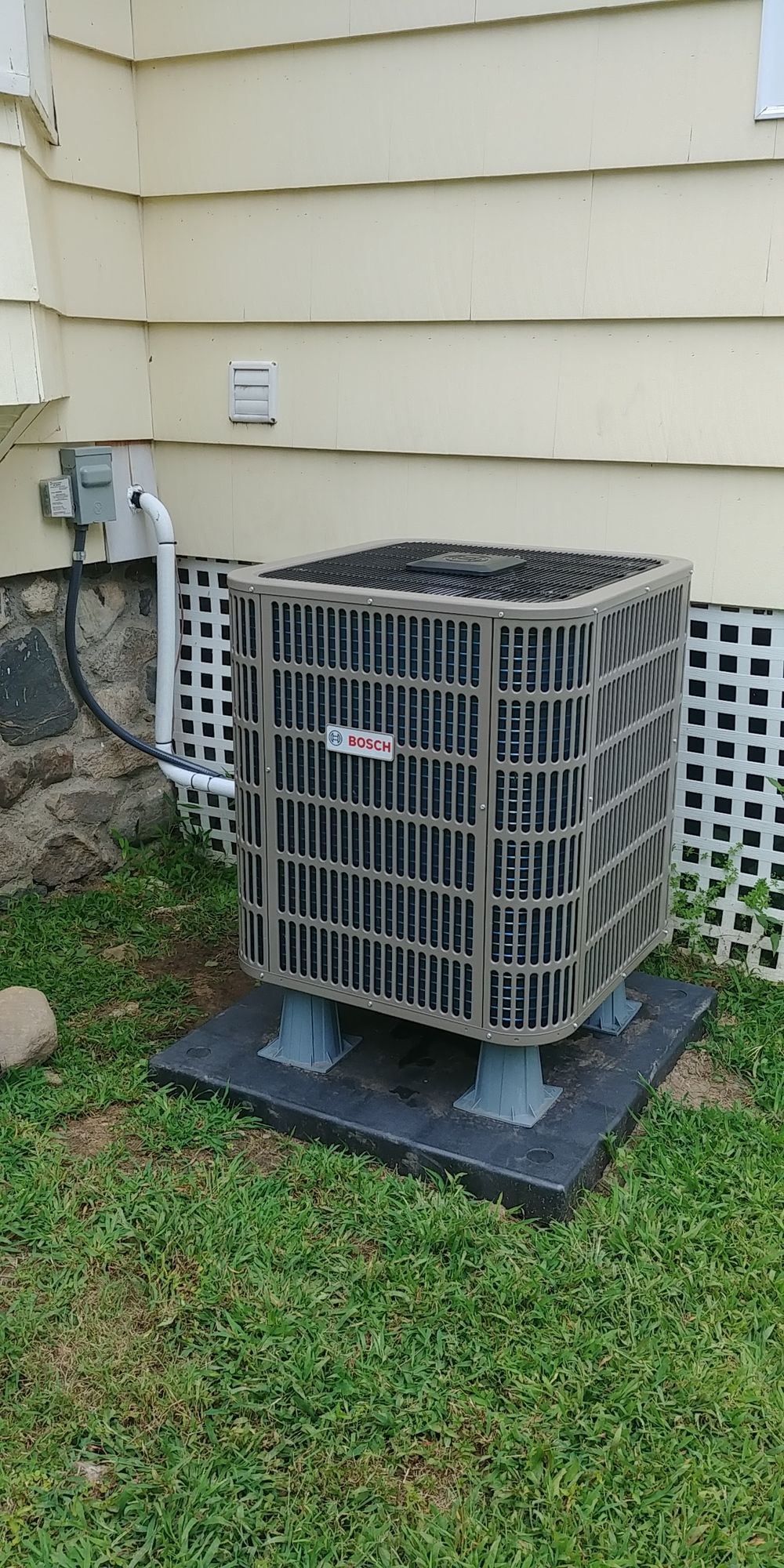 An air conditioner is sitting on the side of a house.