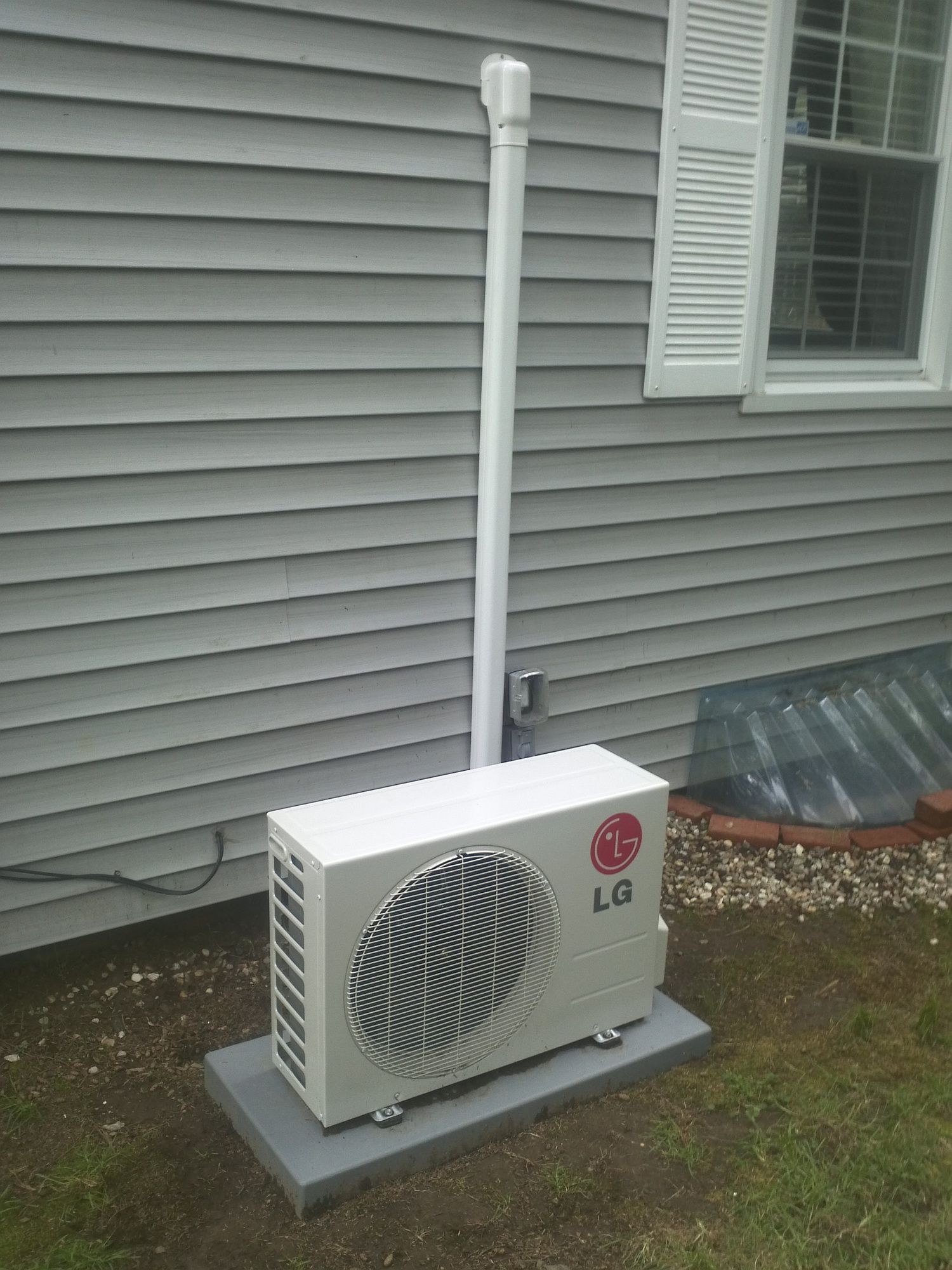 An lg air conditioner is sitting outside of a house