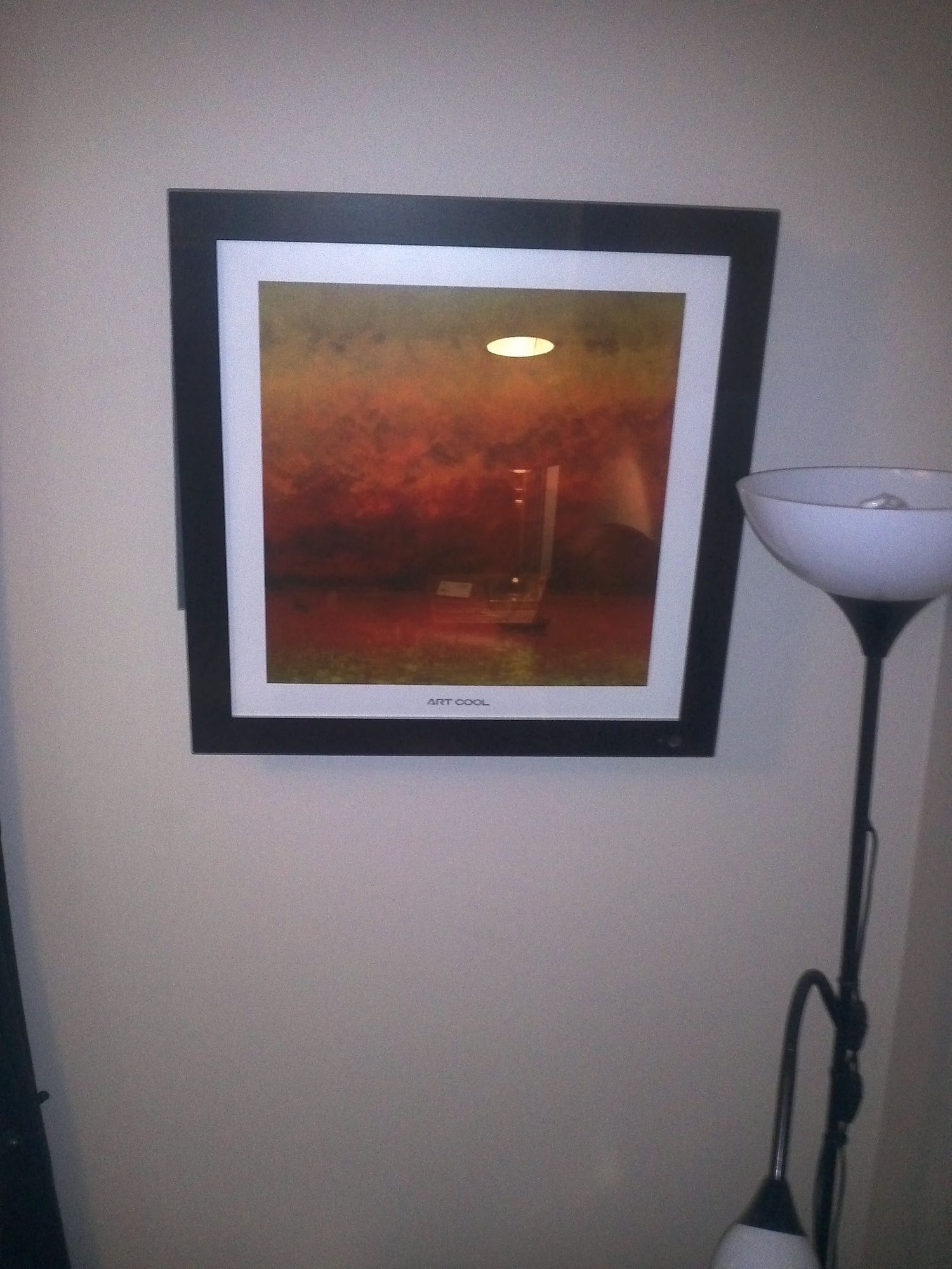 A framed picture on a wall next to a lamp