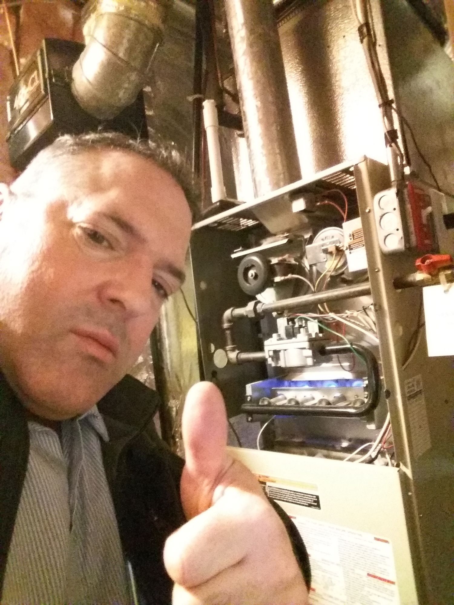 A man is giving a thumbs up in front of an air conditioner