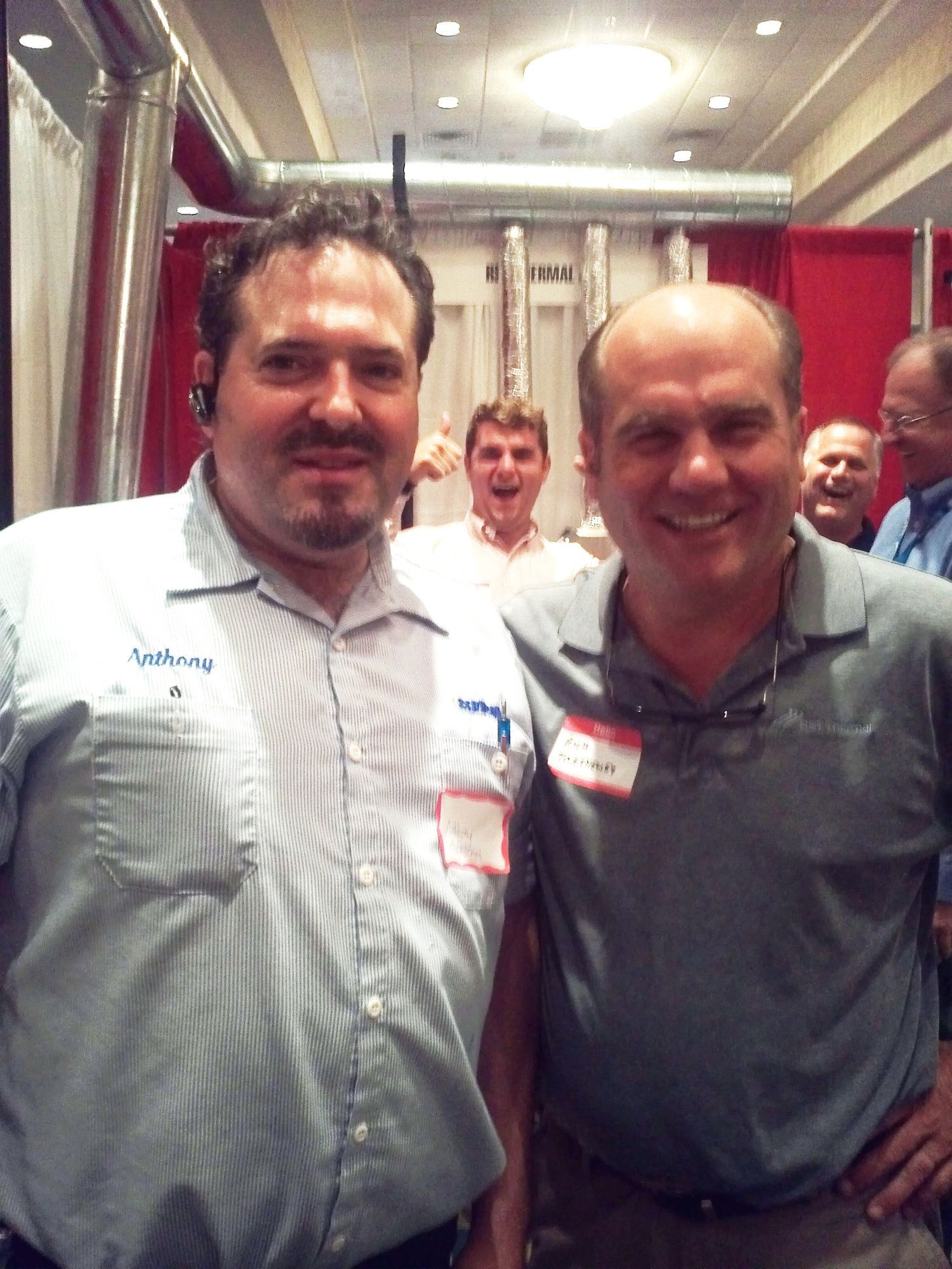 Two men posing for a picture with one wearing a name tag that says james