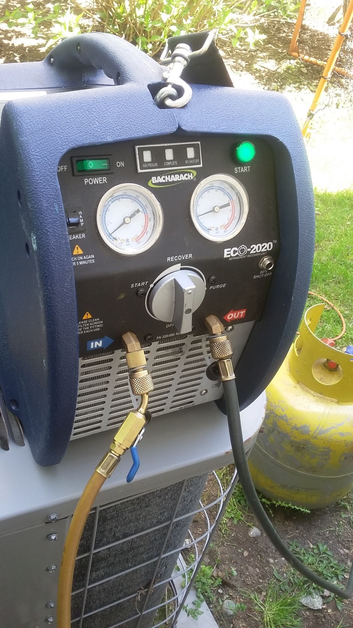 A machine with a hose attached to it is sitting next to a propane tank.