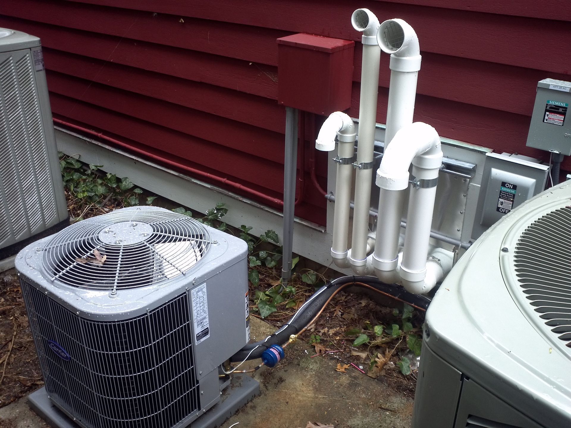 Two air conditioners are sitting next to each other outside of a house