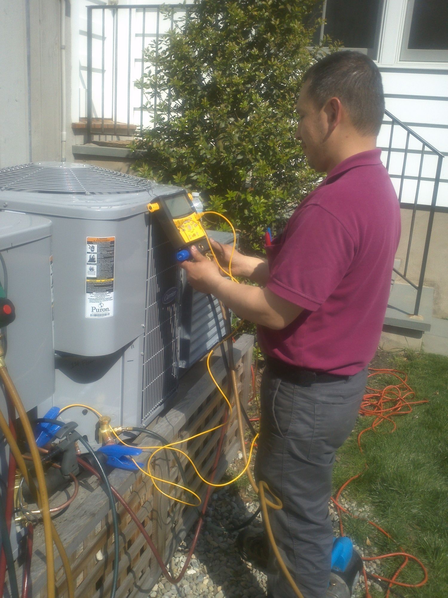 A man is working on an air conditioner outside of a house.