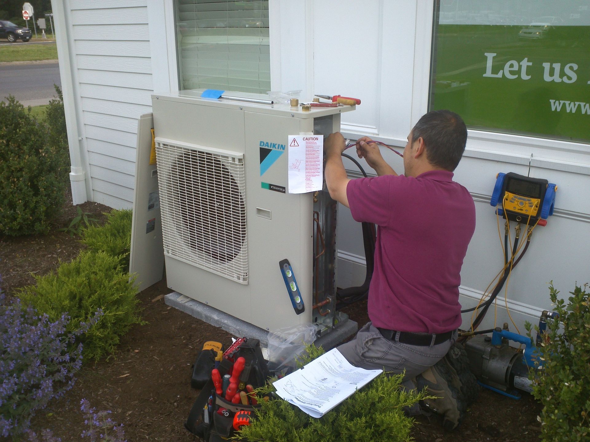 A man is working on an air conditioner outside of a building