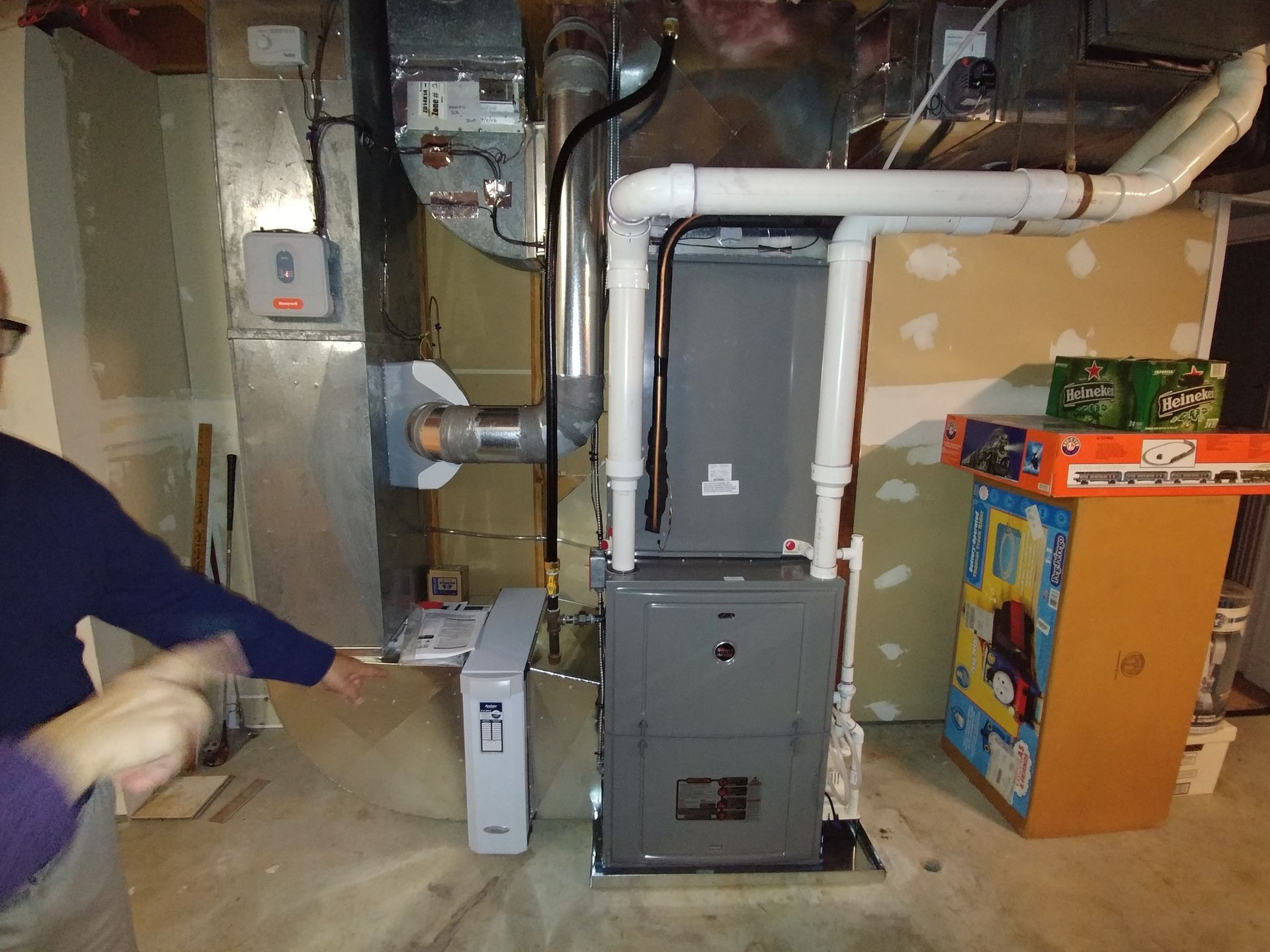 A man is standing in a basement next to a furnace