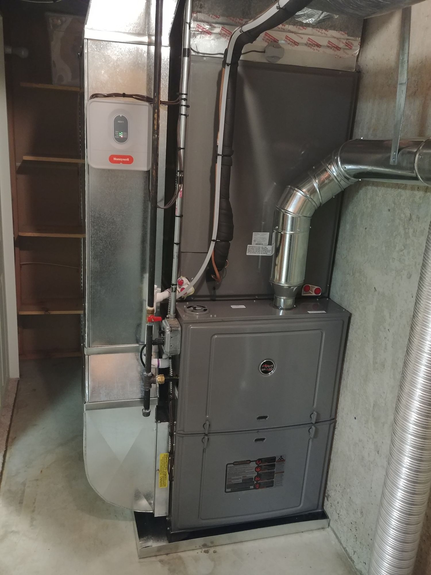 A furnace is sitting in a basement next to a staircase.