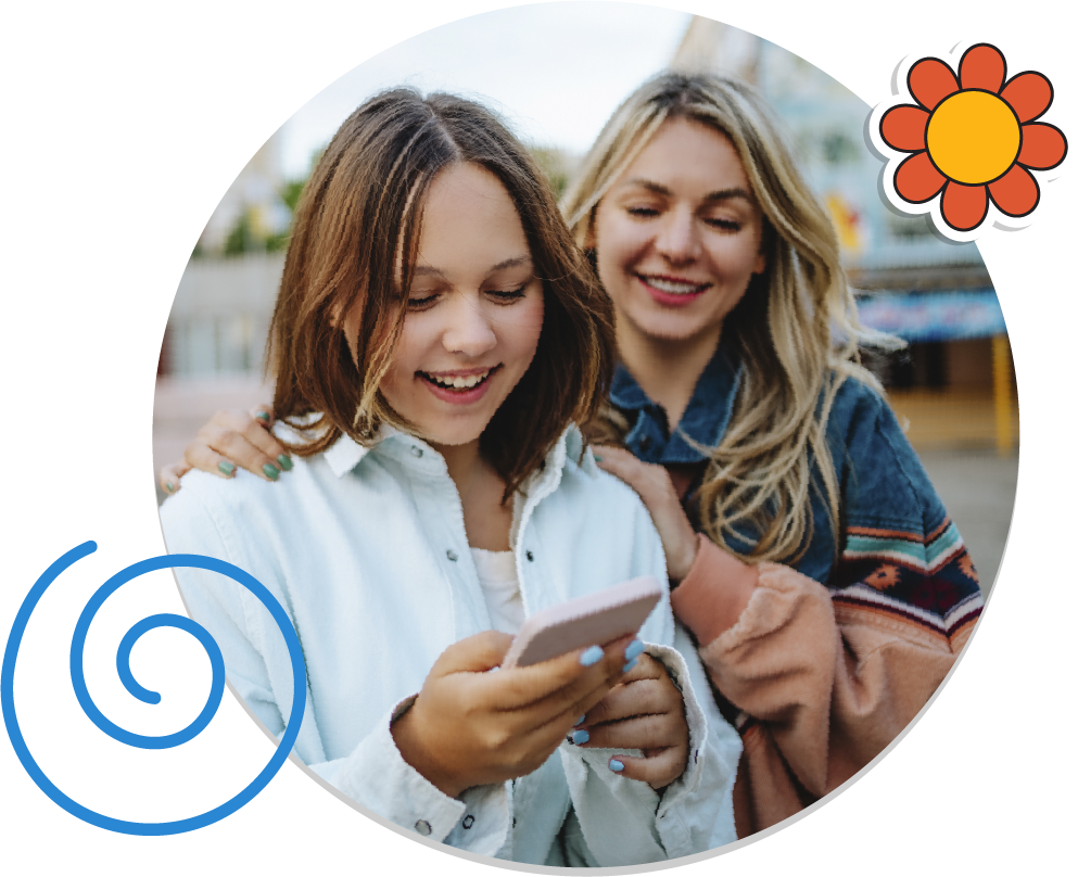 A woman and her teenage daughter are smiling and looking at a cell phone.