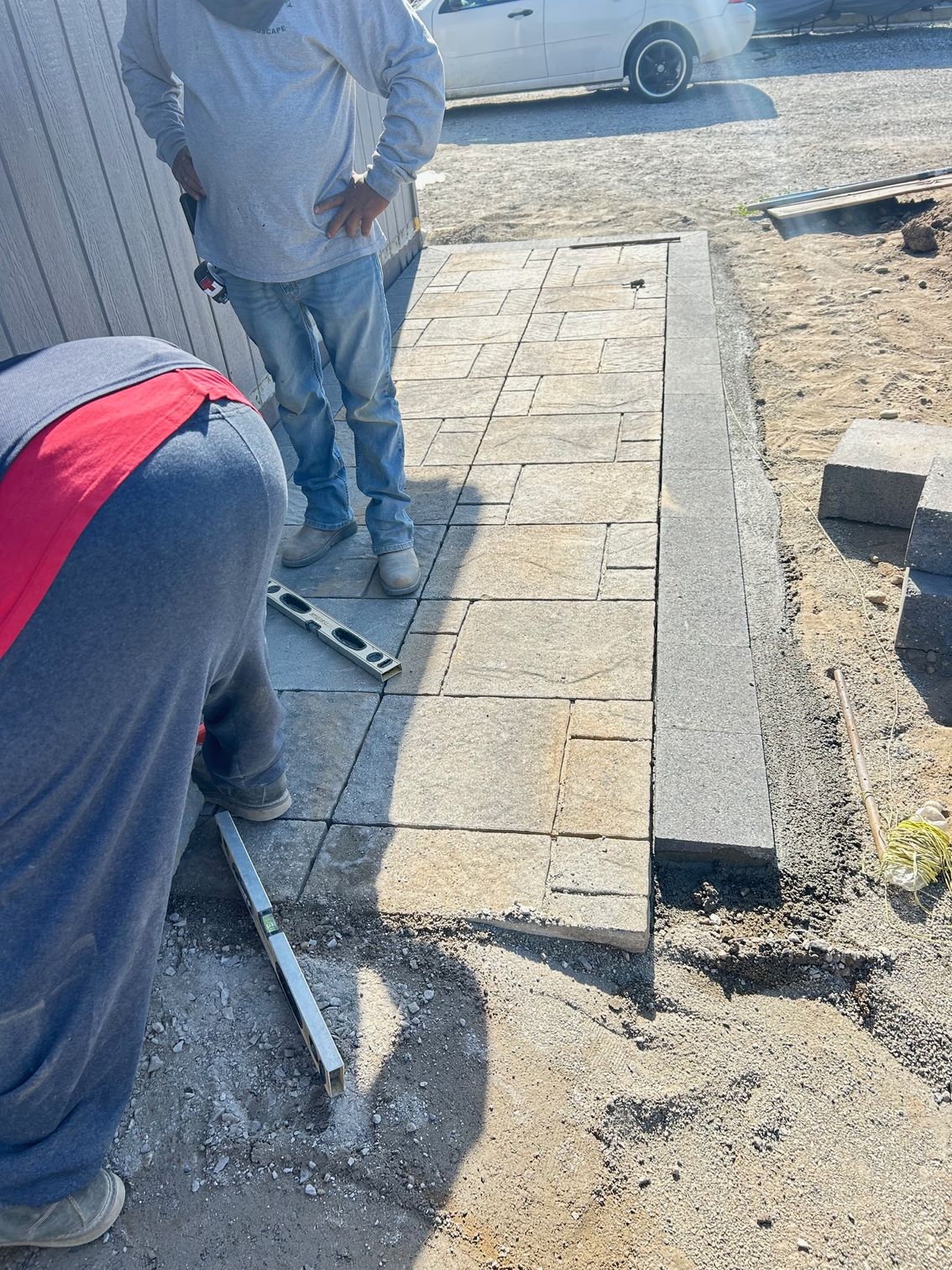 Family-owned crew setting edge restraints and leveling base before installing paver patio in East Wenatchee