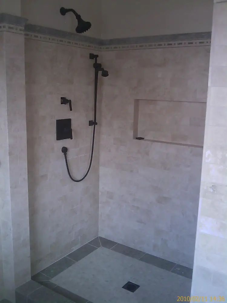 Bathroom sink with black faucet, water running, marble countertop, black accessories, and rectangular mirror.