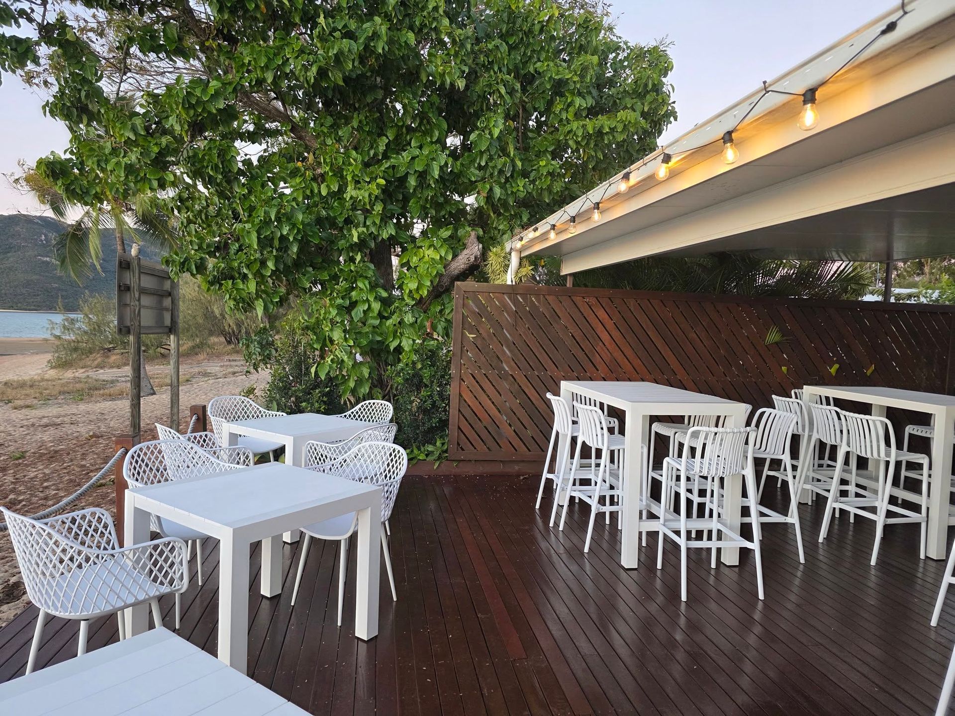 Outdoor Patio With White Tables and Chairs — The Beach Bar and Restaurant at Montes in Cape Gloucester, QLD