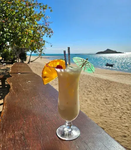 Cocktail with pineapple slice and parasol on beach — The Beach Bar and Restaurant at Montes in Cape Gloucester, QLD