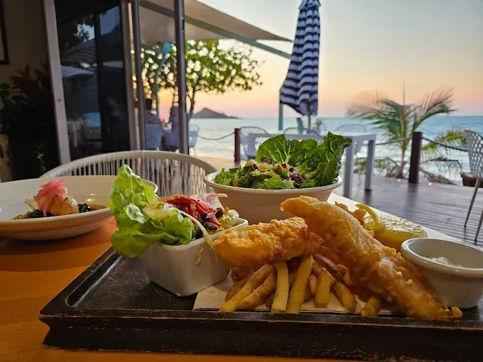 Fish and chips with salad served on a beachfront patio — The Beach Bar and Restaurant at Montes in Cape Gloucester, QLD