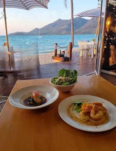 Table with plates of food, salad, and a beach view — The Beach Bar and Restaurant at Montes in Cape Gloucester, QLD