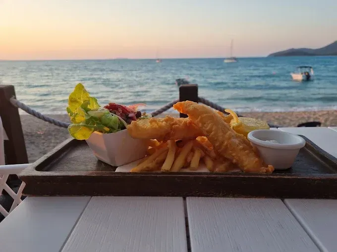 Fish and chips meal with salad, ocean view at sunset — The Beach Bar and Restaurant at Montes in Cape Gloucester, QLD