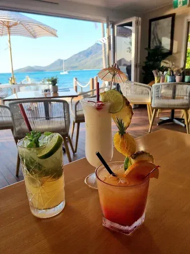 Three cocktails on a wooden table, overlooking a ocean view — The Beach Bar and Restaurant at Montes in Cape Gloucester, QLD