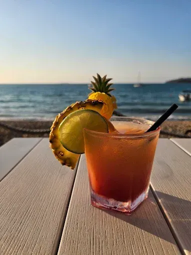 Orange and red drink with pineapple and lime garnish — The Beach Bar and Restaurant at Montes in Cape Gloucester, QLD