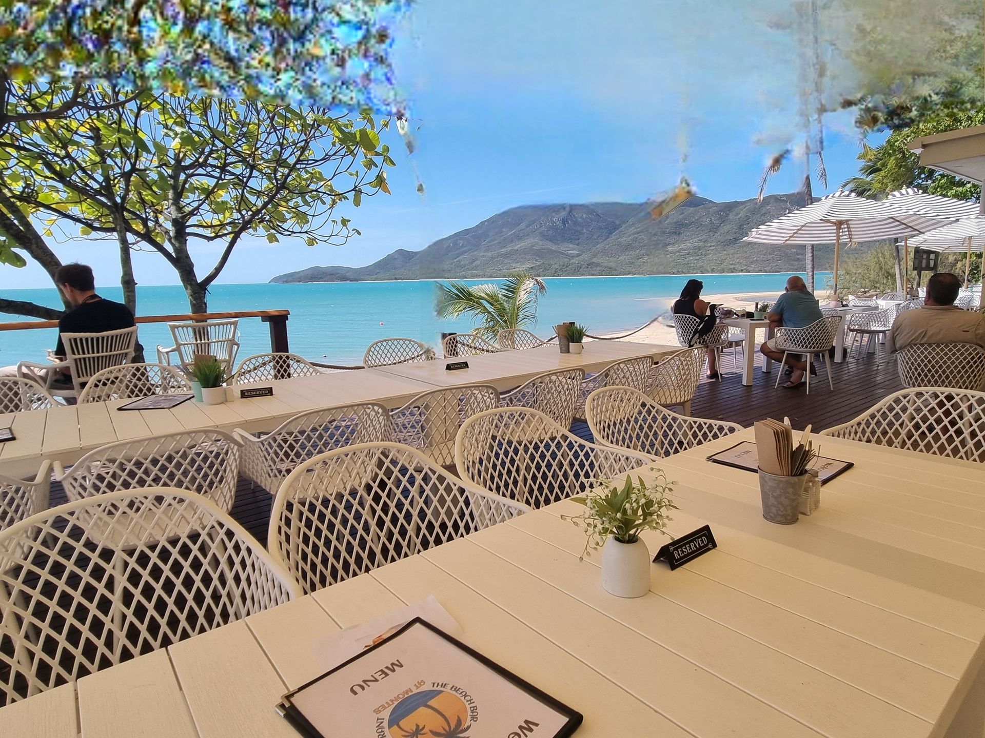 Restaurant With White Tables and Umbrellas on a Beach — The Beach Bar and Restaurant at Montes in Cape Gloucester, QLD