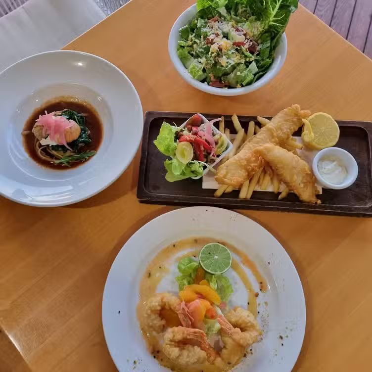 Wooden table set with several dishes — The Beach Bar and Restaurant at Montes in Cape Gloucester, QLD