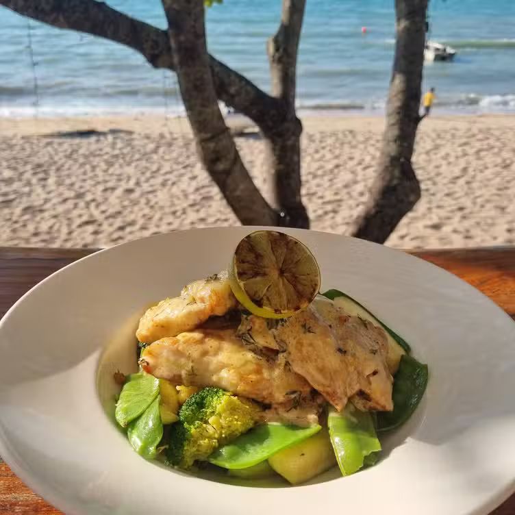 Grilled fish with vegetables with a beach in the background — The Beach Bar and Restaurant at Montes in Cape Gloucester, QLD