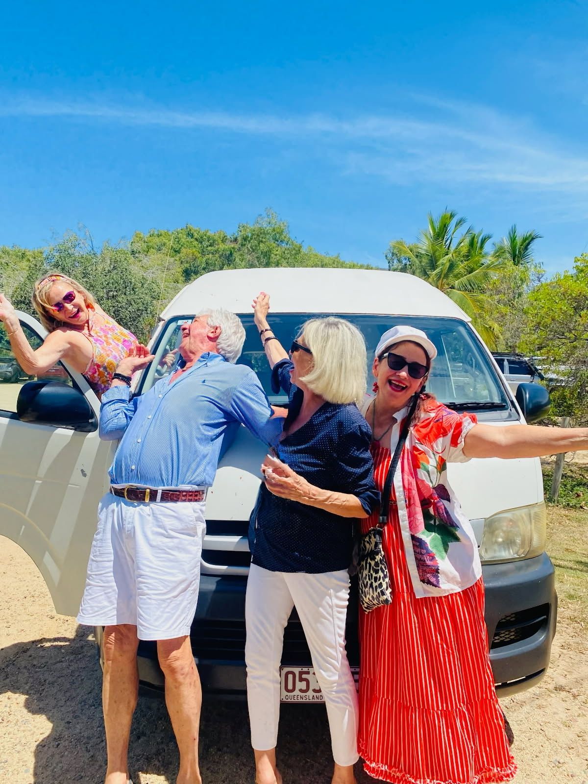 Four People Pose Playfully by a White Van on a Sunny Day — The Beach Bar and Restaurant at Montes in Cape Gloucester, QLD