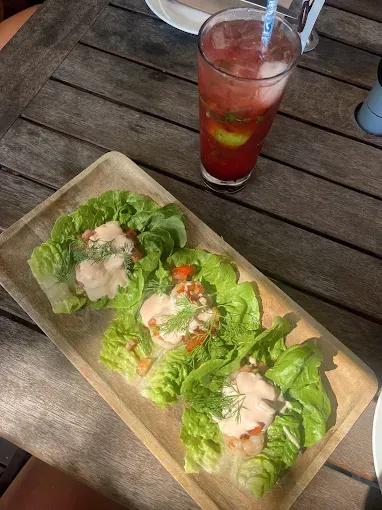 Lettuce wraps and a red cocktail with ice on a wooden table — The Beach Bar and Restaurant at Montes in Cape Gloucester, QLD